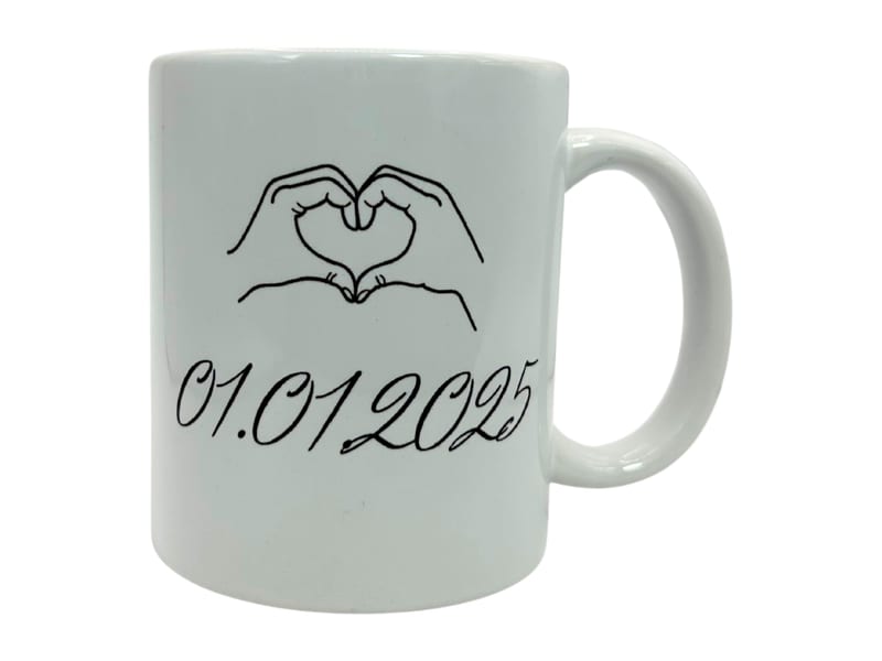 Beispiel: Keramiktasse von LivaGlow, bedruckt mit einem Herz aus zwei Händen und dem Datum 01.01.2025
